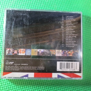Puede incluir: Una caja de CD con fondo negro y borde blanco. La parte delantera de la caja presenta una foto de una banda. La parte posterior de la caja enumera las canciones del CD, incluyendo "I Can't Explain", "Magic Bus", "Pinball Wizard", "Behind Blue Eyes", "Won't Get Fooled Again", "Love Reign O'er Me", "Squeeze Box", "Who Are You", "You Better You Bet", "Eminence Front", "Real Good Looking Boy", y "It's Not Enough". La caja tambi&eacute;n incluye un c&oacute;digo de barras y el texto "GUM" y "thesho.com GETMUSICCA".