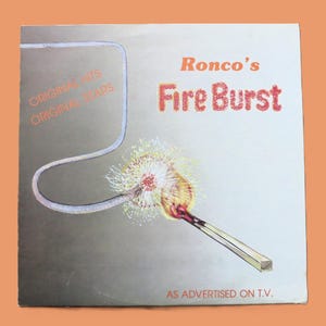 May include: A square vinyl record cover titled Ronco's Fire Burst. The cover features a graphic of a lit match igniting a fuse against a gradient background transitioning from dark gray to white. Text includes Original Hits Original Stars and As Advertised On T.V.