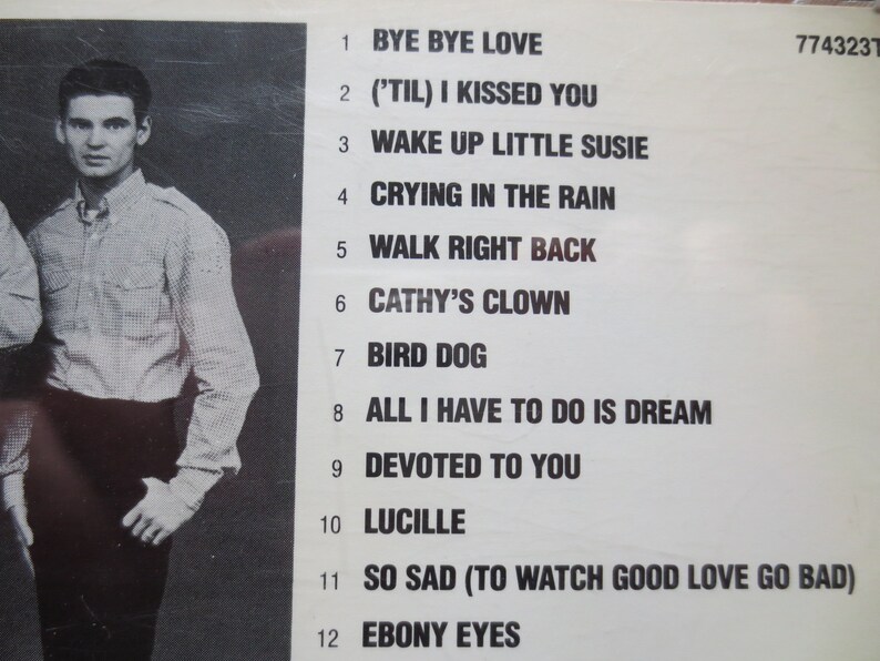 May include: A black and white photograph of a band with a list of 12 song titles. The band members are wearing casual clothing. The song titles include "Bye Bye Love", "('Til) I Kissed You", "Wake Up Little Susie", "Crying In The Rain", "Walk Right Back", "Cathy's Clown", "Bird Dog", "All I Have To Do Is Dream", "Devoted To You", "Lucille", "So Sad (To Watch Good Love Go Bad)", and "Ebony Eyes".