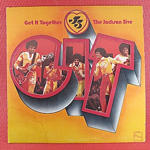 May include: A vinyl record album cover featuring the Jackson 5. The cover is yellow and red with the band's name and album title "Get It Together" in white text. The album cover features a photo of the band members in a circular frame.
