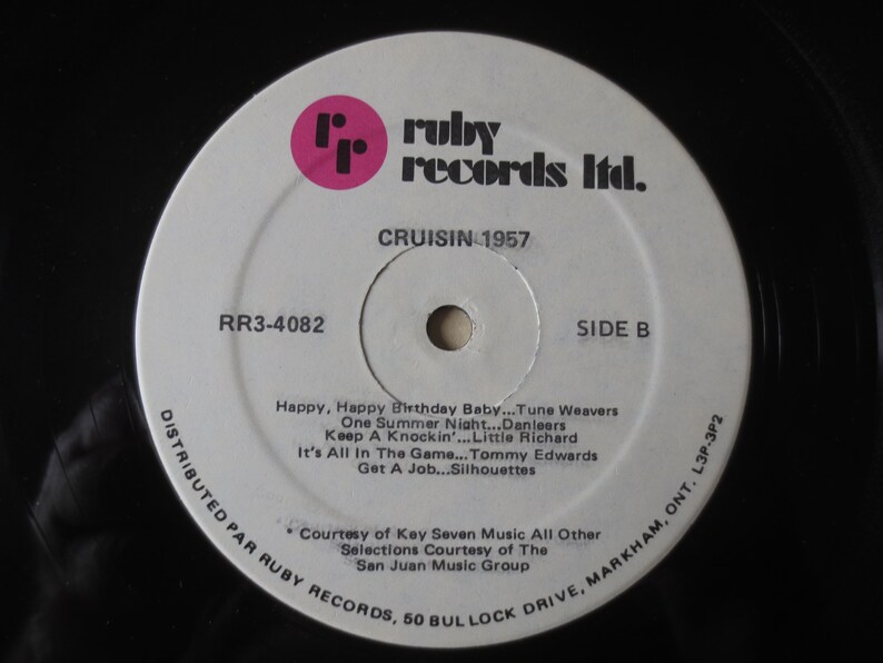 Pu&ograve; includere: Un'etichetta di disco in vinile bianco con un logo "rr" rosa e il testo "ruby records ltd." in nero. Il disco &egrave; intitolato "CRUISIN 1957" e elenca le canzoni sul lato B: "Happy, Happy Birthday Baby... Tune Weavers", "One Summer Night... Danleers", "Keep A Knockin'... Little Richard", "It's All In The Game... Tommy Edwards", "Get A Job...Silhouettes". L'etichetta include anche informazioni di distribuzione: "DISTRIBUTED PAR RUBY RECORDS, 50 BULLOCK DRIVE, MARKHAM, ONT. L3P-3P2" e crediti: "Courtesy of Key Seven Music All Other Selections Courtesy of The San Juan Music Group".