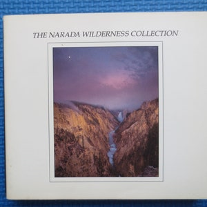 May include: The Narada Wilderness Collection album cover features a photograph of a canyon with a river flowing through it. The sky is a vibrant purple and pink, with a single star visible in the upper left corner.