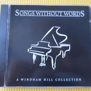 May include: A black CD case with a white outline of a grand piano and the text "Songs Without Words A Windham Hill Collection".
