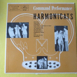 Puede incluir: Una portada de disco de vinilo vintage con un grupo de hombres tocando la armónica. La portada es amarilla y naranja con una forma de corazón blanco en el centro. El texto "Command Performance" y "Harmonicats" está impreso en negro. El disco es de Mercury Records.