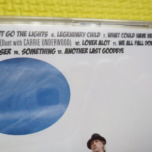 May include: A CD case with a blue background and the text "OUT GO THE LIGHTS", "LEGENDARY CHILD", "WHAT COULD HAVE BEEN LOVE", "YOU* (Duet with CARRIE UNDERWOOD)", "LOVER ALOT", "WE ALL FALL DOWN", "CLOSER", "SOMETHING", "ANOTHER LAST GOODBYE".