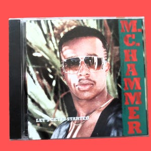 Op de afbeelding: Een muziek-cd-hoesje met het album Let's Get It Started van M.C. Hammer. De hoes toont een portret van een persoon met een grote bril met gouden montuur en een dunne gouden ketting, tegen een achtergrond van groene palmbladeren.