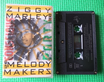Może przedstawiać: Czarna kaseta z żółto-zieloną etykietą. Etykieta zawiera zdjęcie Ziggy'ego Marley'a i tekst "Ziggy Marley and the Melody Makers Conscious Party".