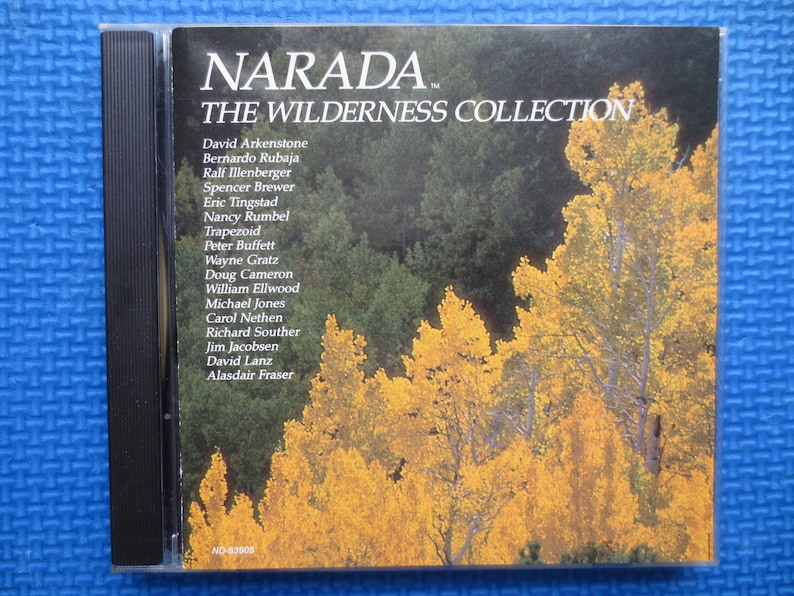 May include: A CD case with a photo of a forest in autumn colors. The text on the case reads "NARADA THE WILDERNESS COLLECTION" and lists the names of various musicians.
