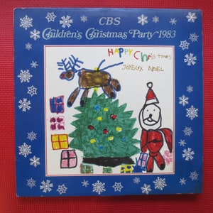 May include: A blue record album cover with a white border featuring a child's drawing of a Christmas tree, reindeer, and Santa Claus. The text on the cover reads "CBS Children's Christmas Party 1983" and "Happy Christmas Joyeux Noel".