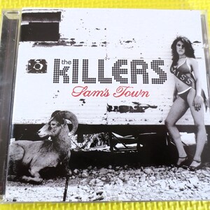 May include: The Killers album cover featuring a black and white image of a woman wearing a "Miss" sash and a ram in the foreground. The album title "Sam's Town" is written in red.