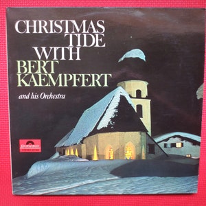 Può includere: Una copertina di un album in vinile vintage con una chiesa innevata con finestre illuminate. Il titolo dell'album è "Christmas Tide with Bert Kaempfert and his Orchestra".