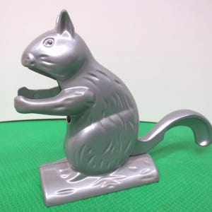 May include: A silver squirrel nutcracker with a detailed design. The squirrel is sitting on a base and has its tail curled around its body.