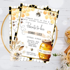 Può includere: Un invito a una festa di baby shower bianco e oro con tema delle api. L'invito presenta un barattolo di miele, api e favi. Il testo sull'invito recita "Si prega di unirsi a noi per una festa di baby shower in onore dei futuri genitori GEMMA + LUCA".
