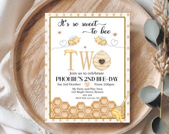 May include: A white invitation card with a gold border and honeycomb pattern. It's so sweet to bee two. Join us to celebrate Phoebe's 2nd Bee-Day. Sat 3rd October from 2:00pm. My Party and Play Area. 123 Maple Street, Boston. RSVP ZOE-123-456-789.