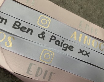 May include: Close-up of several ribbons in shades of pink and gray. The ribbons have text and Instagram logos printed on them in gold and gray. The text includes names and social media handles.