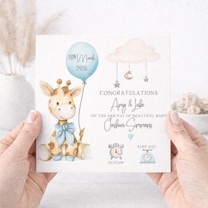 May include: A birth announcement card featuring a watercolour giraffe with a blue bow, a blue balloon labelled 10th March 2026, a pink cloud mobile, and text reading Congratulations Amy & Luke on the arrival of beautiful baby Joshua Summons, 8lbs 3oz.