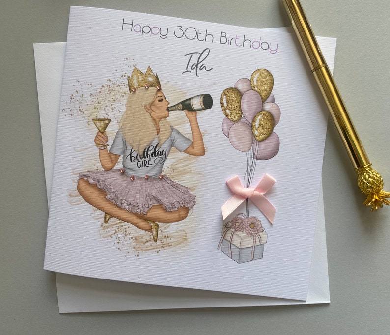 May include: A birthday card with a pink and gold illustration of a woman wearing a crown and a "Birthday Girl" shirt. The card says "Happy 30th Birthday Ida".