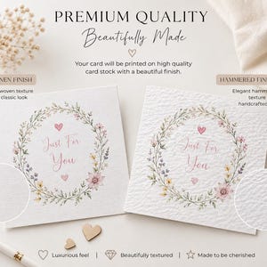 May include: Two square white greeting cards featuring a floral wreath illustration with pink hearts and the text Just For You. One card displays a linen finish with a subtle woven texture, while the other shows a hammered finish with a textured surface.