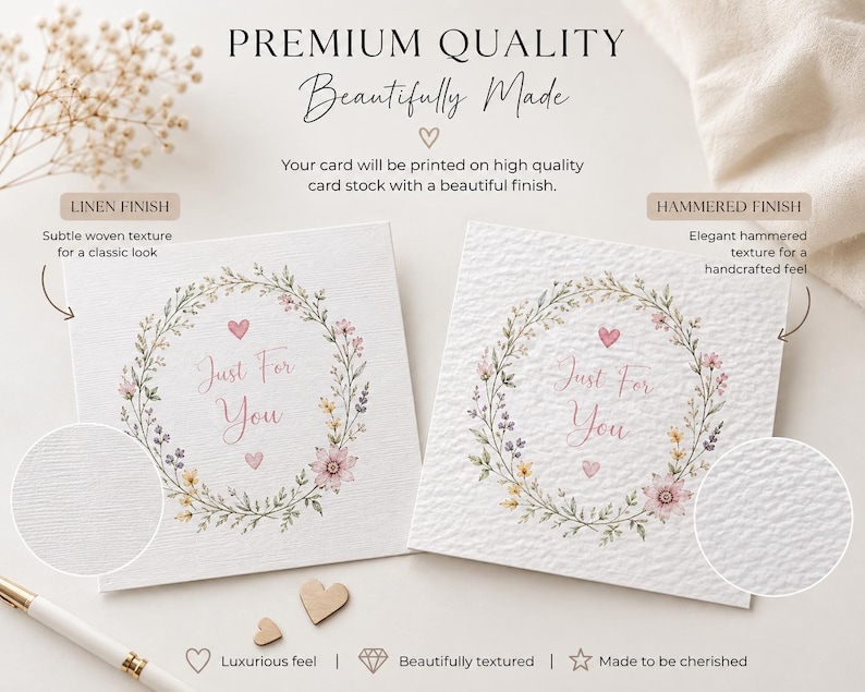 May include: Two square white greeting cards featuring a floral wreath illustration with pink hearts and the text Just For You. One card displays a linen finish with a subtle woven texture, while the other shows a hammered finish with a textured surface.