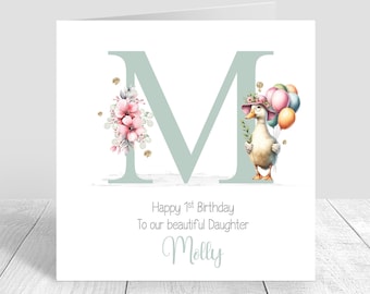 May include: A white card with a green letter M decorated with pink flowers and a duck holding balloons. The card says "Happy 1st Birthday To our beautiful Daughter Molly".