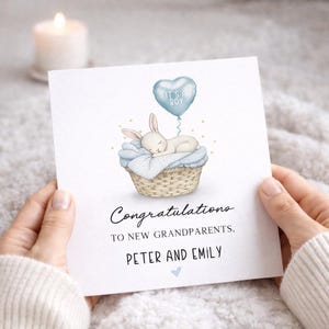 May include: A baby shower greeting card with a watercolor illustration of a sleeping bunny in a basket, a blue balloon that says "It's a Boy", and the text "Congratulations to new grandparents, Peter and Emily".