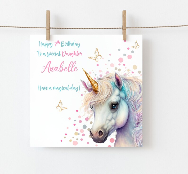 May include: A white unicorn with a gold horn and a rainbow mane and tail. The unicorn is surrounded by pink, gold, and gray confetti. The text "Happy 7th Birthday To a special Daughter Anabelle Have a magical day!" is written on the card.
