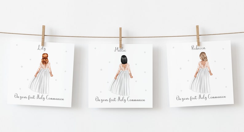 May include: Three framed illustrations of girls in white dresses, hanging from a string with wooden clips. Each illustration features a girl with a different hair color and the text "On your first Holy Communion". The names Lily, Millie, and Rebecca are above each illustration.