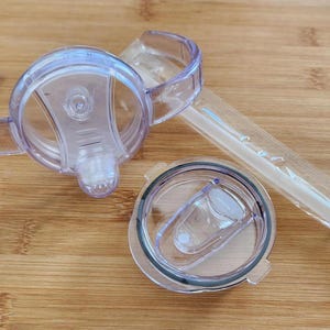 May include: Three clear plastic lids for a tumbler. The lids have a lip for a straw and a handle for easy carrying.