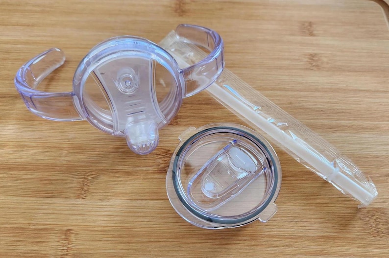 May include: Three clear plastic lids for a tumbler. The lids have a lip for a straw and a handle for easy carrying.