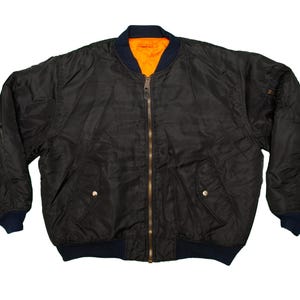 Può includere: Giacca bomber nera con cerniera a tutta lunghezza, due tasche anteriori e colletto e polsini a coste blu navy. L'interno è arancione brillante. Un capo di abbigliamento esterno classico.