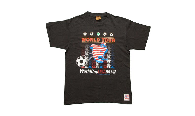 K&ouml;nnte beinhalten: Schwarzes T-Shirt mit einem Aufdruck eines Fu&szlig;balls und dem Text "World Tour WorldCup USA 94".