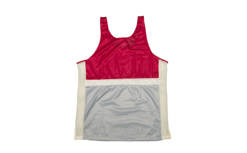 May include: A sleeveless vest top in a colour block design. The top features a red upper section, a white horizontal stripe, and a grey lower section. The sides have vertical white stripes.