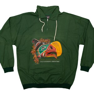 May include: A dark green pullover jacket with a half-zip closure and a drawstring hood. The front features a colorful graphic of a Thunderbird design with text that reads "PRINCE RUPERT CANADA THUNDERBIRD DESIGN".