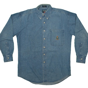 Può includere: Camicia di jeans blu chiaro con bottoni e maniche lunghe. Presenta colletto button-down, taschino sul petto con stemma ricamato e polsini con bottoni. Realizzata in denim di peso medio, adatta a diverse occasioni.