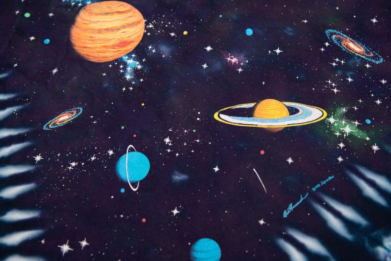 May include: A colorful space-themed illustration featuring planets, galaxies, and stars against a dark blue background. The artwork includes a large orange planet, a planet with rings, and several blue planets. The image is signed in the lower right corner.