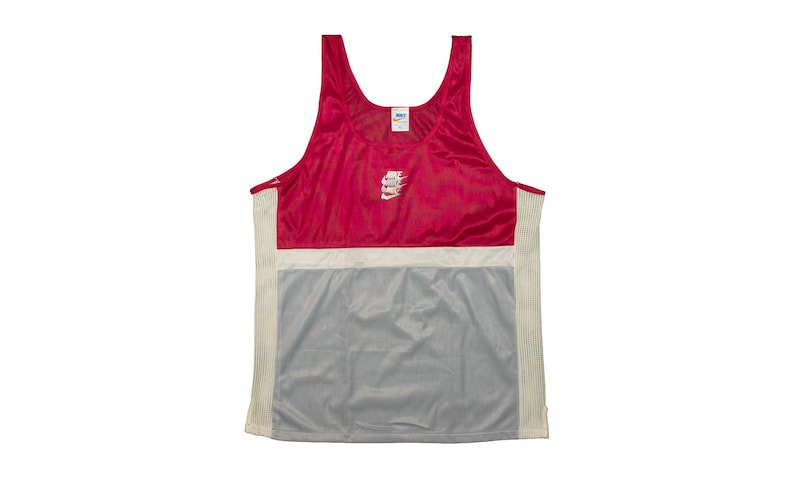 May include: A sleeveless athletic vest in red, white, and grey. The vest features a red upper section, a white horizontal band, and a grey lower section. The Nike logo is visible on the chest.