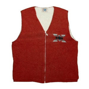 Peut inclure: Un gilet rouge avec un col en V et une fermeture éclair sur toute la longueur. Le gilet a un intérieur blanc et un petit motif brodé sur le devant. Le motif présente des formes géométriques noires, blanches et vertes.