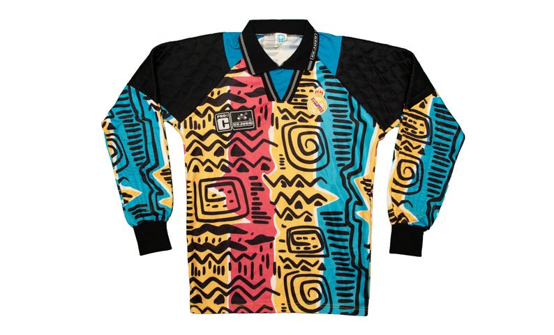 May include: A long-sleeved jersey with a vibrant, abstract pattern. The shirt features a black collar and sleeves, with a colorful design of yellow, red, and blue shapes. The jersey has a V-neck and includes patches with text.