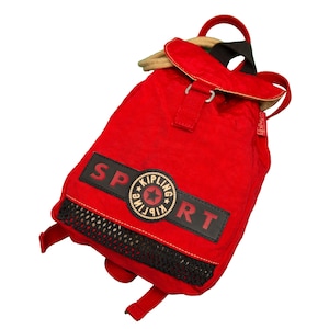 May include: Red Kipling brand backpack with a black mesh pocket and a black patch that says "SPORT" with a Kipling logo in the center.