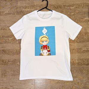 May include: White t-shirt with a blue background featuring a cartoon character with yellow hair, a red bow, and a white animal companion. The character has a thought bubble above their head with an infinity symbol.