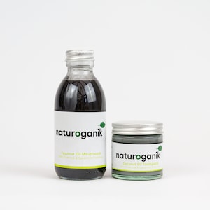 May include: Two glass bottles containing black liquid. The larger bottle is labelled "naturoganik Coconut Oil Mouthwash with Charcoal & Spearmint Freshness". The smaller bottle is labelled "naturoganik Coconut Oil Toothpaste with Charcoal & Spearmint Freshness".