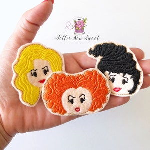 May include: Three embroidered felt patches featuring the faces of the Sanderson sisters from the movie Hocus Pocus. The patches are yellow, orange, and black.
