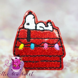 May include: Red glitter dog house with a white dog on top. The dog house has a string of colorful lights around it.