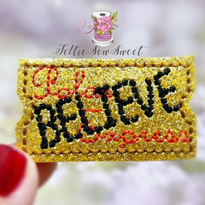 May include: Gold glitter iron-on patch with black and red embroidery that says "Believe".