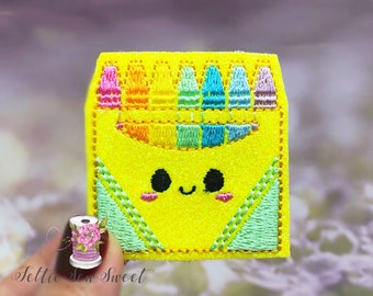 May include: A yellow felt box with a smiling face and a row of colorful crayons inside. The box is decorated with green felt trim.