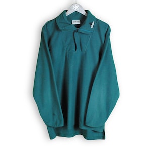 May include: A teal green fleece pullover with a snap button closure and a small Adidas logo on the collar.