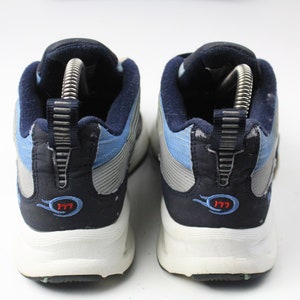 May include: A pair of blue and gray athletic shoes with white soles. The shoes have a blue and gray fabric upper with a silver stripe and a red "177" logo on the back.