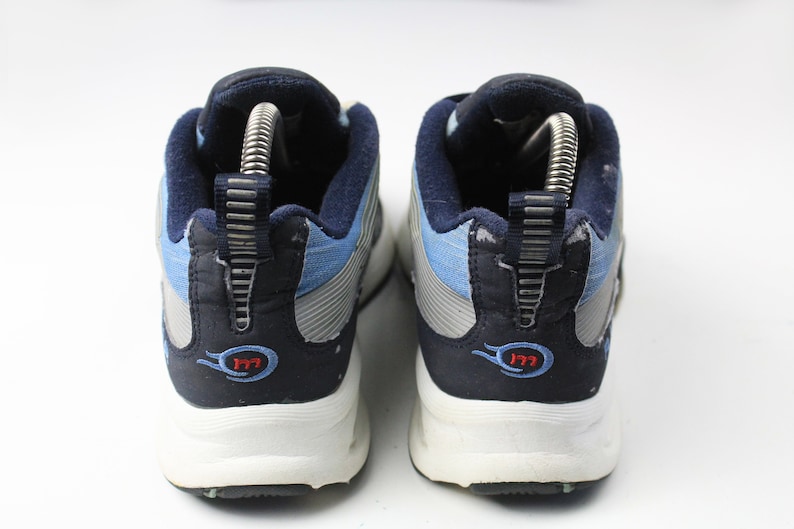 May include: A pair of blue and gray athletic shoes with white soles. The shoes have a blue and gray fabric upper with a silver stripe and a red "177" logo on the back.
