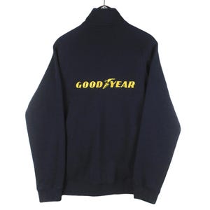 May include: A navy blue zip-up sweatshirt with a yellow Goodyear logo on the back.