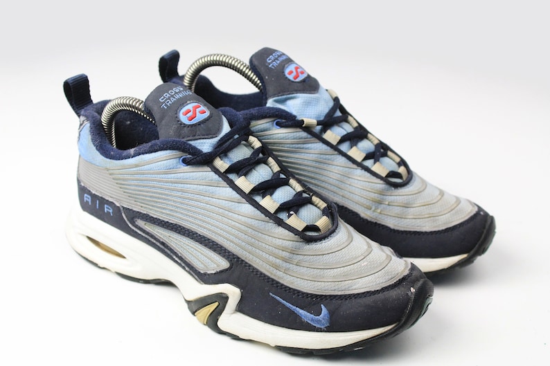 May include: A pair of blue and navy blue Nike Air Cross Training sneakers with a white sole and a silver shoelace holder.